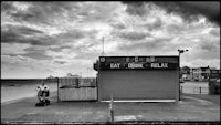 a black and white photo of a restaurant on the beach