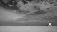 a black and white photo of a beach with a lifeguard tower