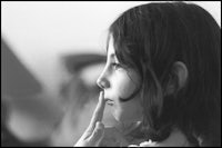 a black and white photo of a girl with her finger on her nose
