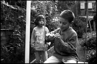 two children playing on a swing in a garden