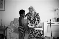 an old woman reading a book to a young boy