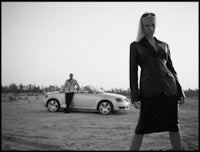 a woman standing next to a car in the desert
