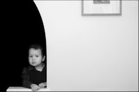 a little boy peeking out of an archway